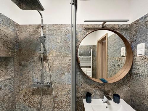 扎马迪Sunshine Resort Blue Apartman的带淋浴、盥洗盆和镜子的浴室