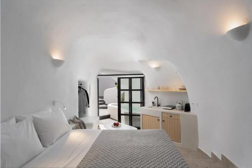 梅加洛克里Nisó Cave Suites的白色卧室配有床和镜子