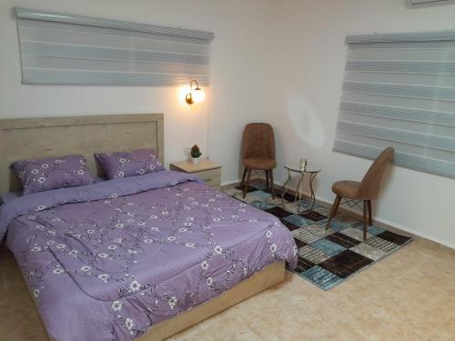 Ein Kinyaגבעת האלון的一间卧室配有一张紫色的床和两把椅子
