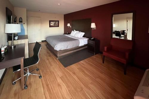 圣安东尼奥Quality Inn & Suites I-10 near Fiesta Texas的酒店客房配有一张床、一张桌子和一把椅子。
