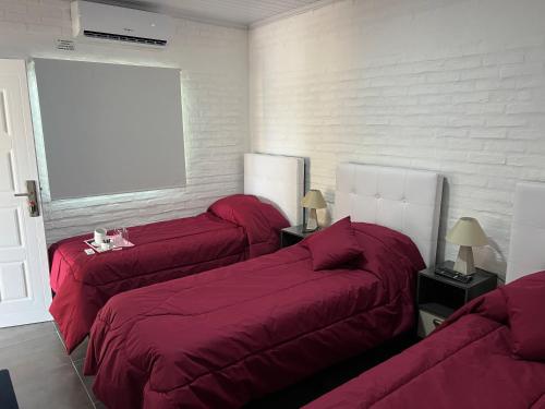 派桑杜Apart del Este Loft 6的一间卧室设有三张床、红色床单和窗户