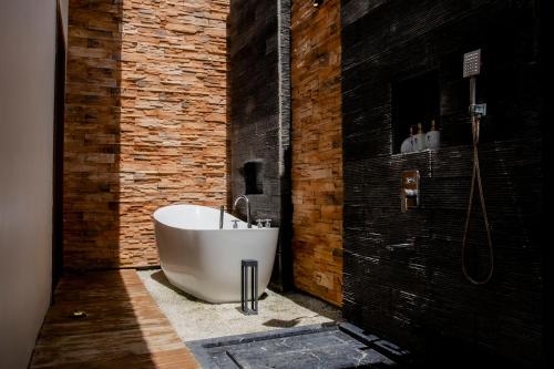 邦劳Amphitrite Resort的浴室设有白色浴缸,毗邻砖墙