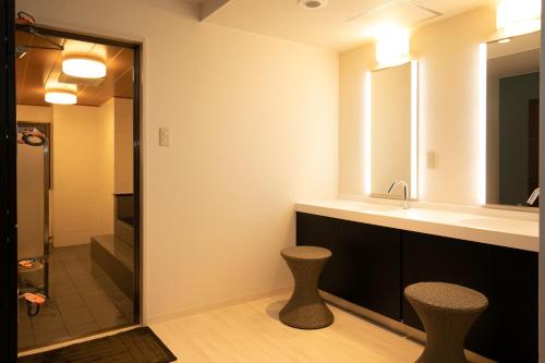 高知高知日出酒店的浴室设有水槽、两张凳子和镜子
