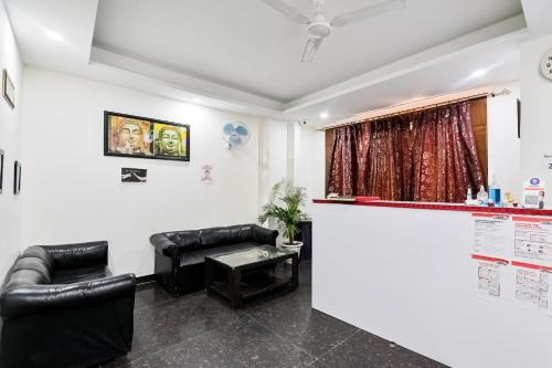 新德里OYO 72284 Premium Rooms Chhatarpur的一间设有黑色皮椅和柜台的等候室