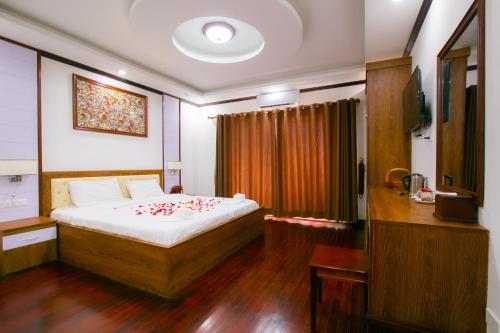万象Nana Vientiane Hotel的一间卧室,床上有红色的鲜花