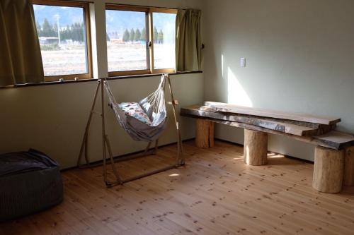 安昙野市Azumino Fukuro Guesthouse - Vacation STAY 21913v的客房设有吊床、桌子和窗户。