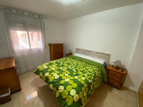 塔拉戈纳Joan XXIII Apartment的一间卧室配有一张带绿色和黄色床罩的床。