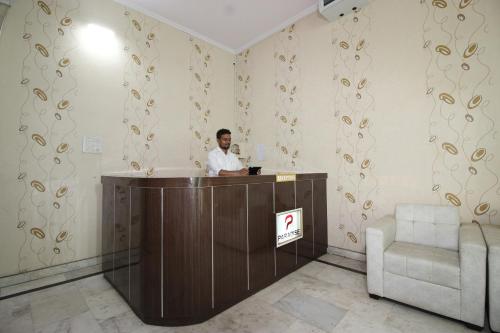RāmnagarSuper Capital O Hotel Paradise Residency的站在一个房间前台的一个男人