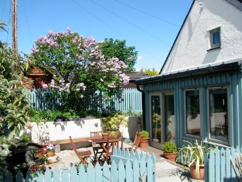 福里斯Driftwood Cottage, Findhorn Village的房屋设有围栏、木桌和长凳