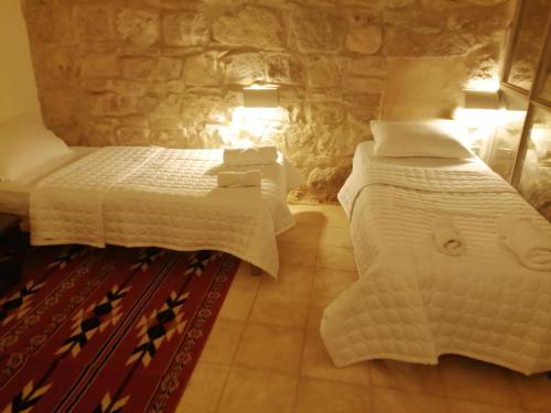 达纳Dana Gardens Hotel的一间卧室设有两张床和石墙