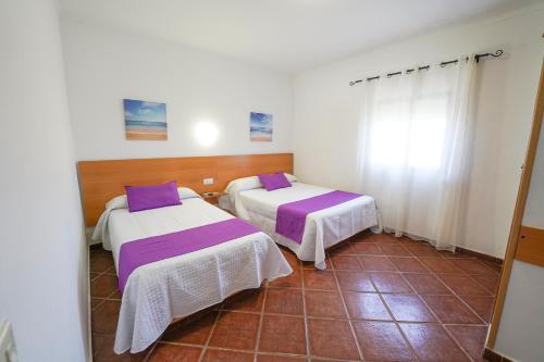 科尼尔-德拉弗龙特拉双子公寓的紫色床单的客房内的两张床
