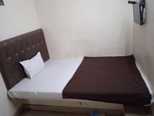 孟买Hotel janata Residency的一张小床,位于一间设有棕色床头板的小房间