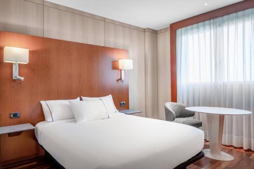 韦尔瓦韦尔瓦万豪AC酒店的酒店客房设有一张白色大床和一张桌子。