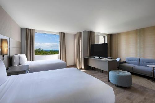 坎昆Residence Inn by Marriott Cancun Hotel Zone的酒店客房配有一张床、一张书桌和一台电视。