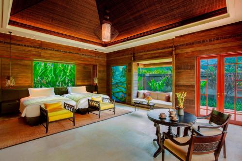 乌布Mandapa, a Ritz-Carlton Reserve的一间卧室配有两张床和一张桌子及椅子