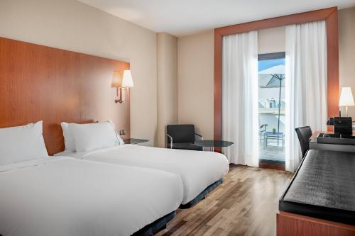 巴达霍斯巴达霍斯万豪AC酒店的配有一张床、一张书桌和一扇窗户的酒店客房