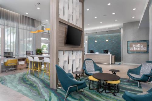 奥兰多TownePlace Suites By Marriott Orlando Southwest Near Universal的大堂设有椅子、桌子和电视。