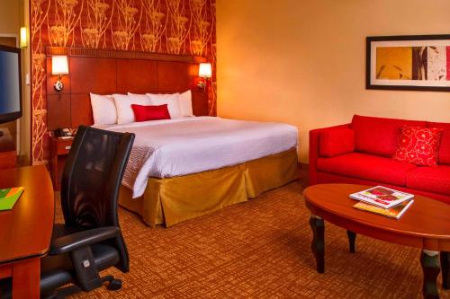 弗吉尼亚海滩维珍利亚诺福克海滩万怡酒店的酒店客房,配有一张床和一张红色的沙发