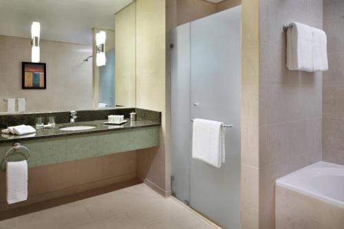 科威特科威特城万怡酒店的浴室配有盥洗盆、镜子和浴缸