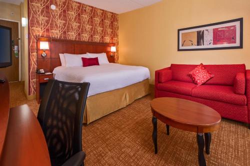 里士满Courtyard by Marriott Richmond West的酒店客房,配有一张床和一张红色的沙发