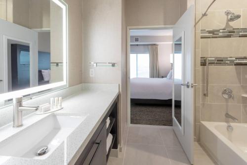 Waite ParkResidence Inn by Marriott St. Cloud的一间带两个盥洗盆和淋浴的浴室以及一张床