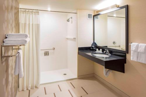 卡尔加里Fairfield Inn & Suites by Marriott Calgary Downtown的带淋浴、盥洗盆和镜子的浴室