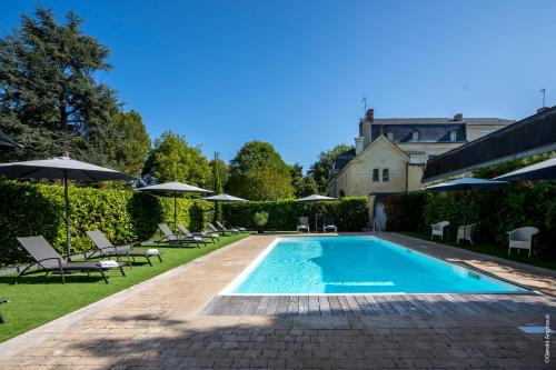 索米尔Château la Comtesse de Loire的庭院内带椅子和遮阳伞的游泳池