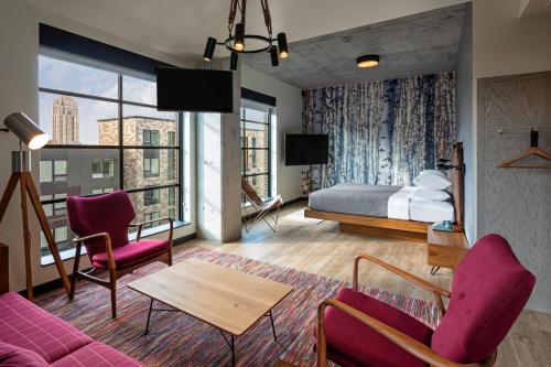 明尼阿波利斯Moxy Minneapolis Downtown的酒店客房配有一张床、一张沙发和椅子。