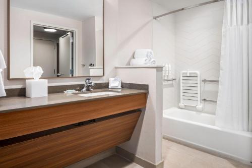堪萨斯城Fairfield by Marriott Inn & Suites Kansas City North, Gladstone的一间带水槽、浴缸和镜子的浴室