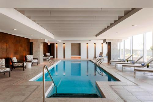 圣亚森特Sheraton Saint-Hyacinthe Hotel的酒店大堂的游泳池,配有桌椅