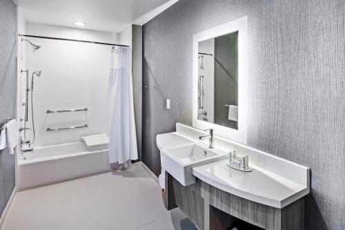 塔尔萨塔尔萨塔尔萨丘陵万豪春季山丘套房酒店的白色的浴室设有水槽、浴缸和镜子