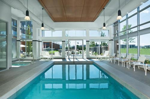 沃恩沃恩西南元素酒店的室内游泳池设有白色的椅子和窗户。