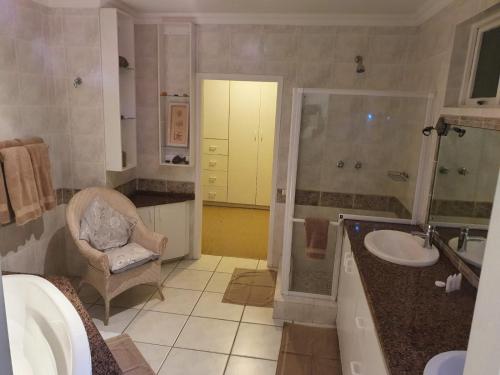 马盖特Ingwe Manor Guesthouse的一间带水槽、淋浴和椅子的浴室