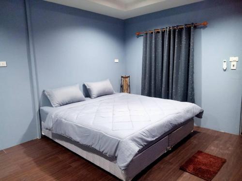 Ban Don Klangเฮือนพรนาคา โฮมสเตย์的一间卧室配有一张带蓝色墙壁的大床