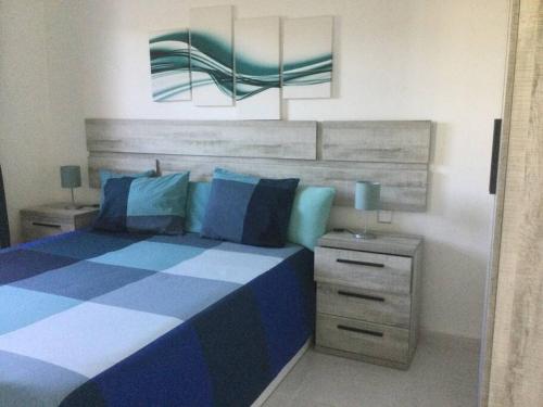 查德尔帕罗奥Natural y sano: Charco del Palo的卧室配有蓝色和白色的床以及床头柜。