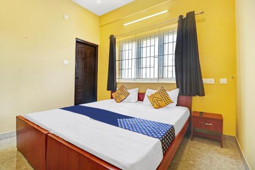 哥印拜陀SPOT ON Kayal Residency的一间卧室设有一张黄色墙壁和窗户的床