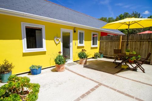 马拉扎恩Krissie's的黄色的房子,配有桌子和雨伞