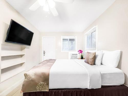 好莱坞The Oasis的白色卧室设有一张大床和一台平面电视。