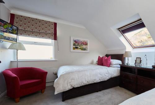 杜林Luxury Lodges in Doolin Village with Hot Tubs的一间卧室配有一张床和一张红色椅子