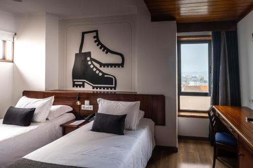圣若昂达马德拉A. S.圣若昂-马德拉酒店的酒店客房的墙上设有两张带靴子的床。