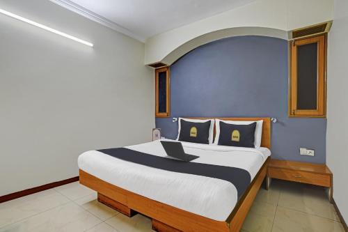 印多尔Townhouse OAK Utsav Residency的一间卧室配有一张带笔记本电脑的床