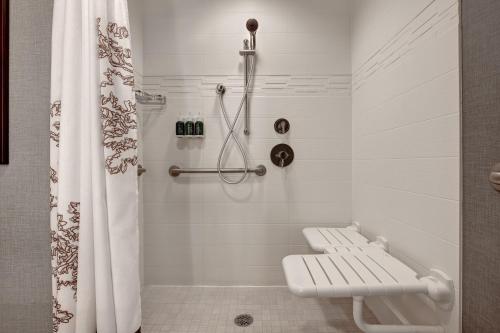 普尔曼铂尔曼原住客栈酒店的一间带长凳和淋浴帘的浴室