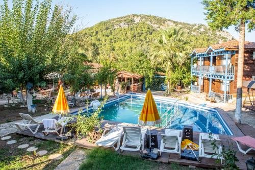 奥林波斯Olympos Çınar Hotel的房屋前的带椅子和遮阳伞的游泳池