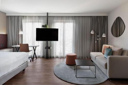 慕尼黑慕尼黑东万怡酒店的客厅配有床、沙发和电视。
