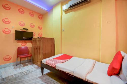 RourkelaSuper OYO Hotel Priyal Amrit Sagar的一间卧室配有一张床、一把椅子和电视。