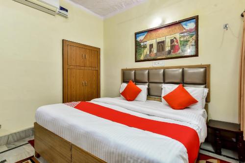 焦特布尔Super OYO Dev Villas Guest House的一间卧室配有一张带橙色枕头的大床