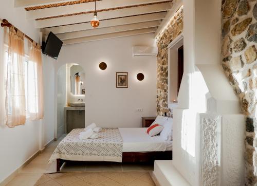 Lagoúdi ZíaTramonto Villa的一间卧室设有一张床和石墙