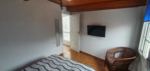 布埃乌Bueu的一间卧室配有一张床,墙上配有电视