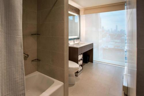 纽约纽约曼哈顿/切尔西万怡酒店的浴室配有卫生间、盥洗盆和浴缸。