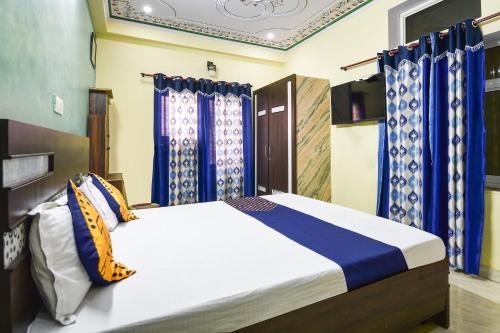 斋浦尔OYO Hotel Rajputana Homestay的一间卧室配有蓝色窗帘的床